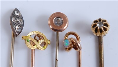 Lot 2552 - A collection of five yellow metal stick pins,...