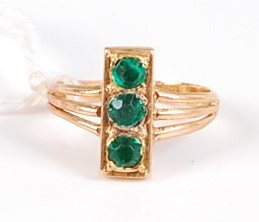 Lot 319 - A yellow metal and green hardstone three stone...