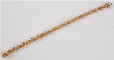 Lot 1219 - A yellow metal diamond line bracelet, the...