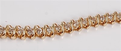 Lot 1220 - A yellow metal diamond line bracelet, the...