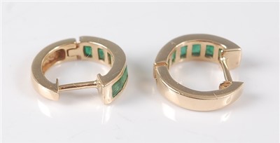 Lot 2645 - A pair of yellow metal and emerald huggy hoop...