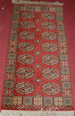 Lot 1144 - A Persian style red ground Bokhara hall rug,...