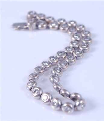 Lot 2172 - An 18ct white gold diamond line bracelet,...
