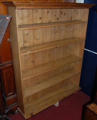 Lot 1099 - A pine freestanding open bookshelf, raised on...