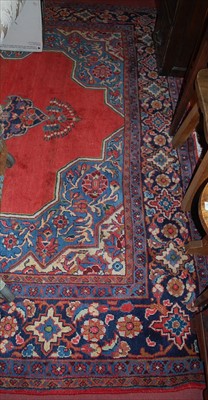 Lot 1149 - A large Persian red ground woollen rug, having...