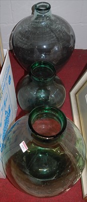 Lot 1082 - Three various green tinted glass carboys