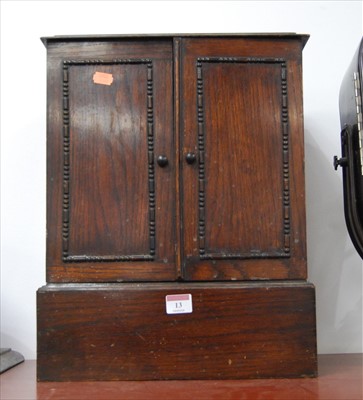 Lot 13 - A 1930s oak table cabinet, enclosed by a pair...