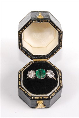 Lot 1193 - A white metal, emerald and diamond three-stone...