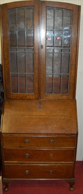 Lot 1103 - A 1930s oak and lead glazed bureau bookcase,...