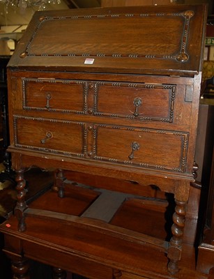 Lot 1262 - A 1920s moulded oak writing bureau raised on...