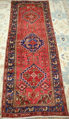 Lot 1504 - A Persian woollen hall runner, the red ground...