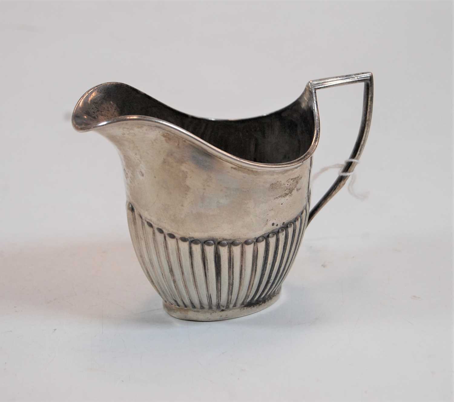 Lot 246 - A silver cream jug of half reeded oval helmet...
