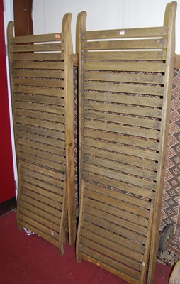 Lot 1162 - A pair of faded slatted teak sun loungers,...
