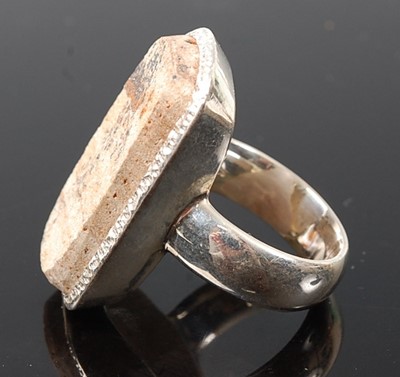 Lot 2576 - A white metal dress ring, featuring a rough...