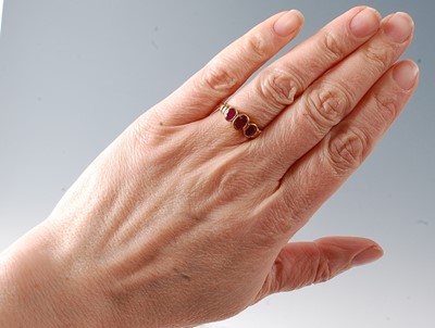Lot 2730 - A 9ct yellow gold ruby three-stone ring,...
