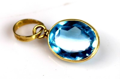 Lot 2512 - A yellow metal oval blue topaz pendant, the...