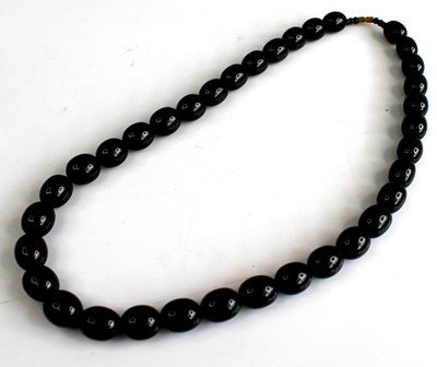 Lot 2561 - A single row black bead necklet, having thirty-...