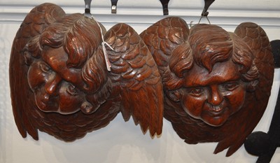 Lot 651 - A pair of oak wall masks each carved as winged...