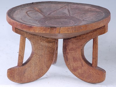 Lot 155 - An African hardwood stool, the dished seat...
