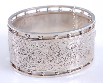 Lot 2569 - A white metal oval hinged cuff bangle, half...