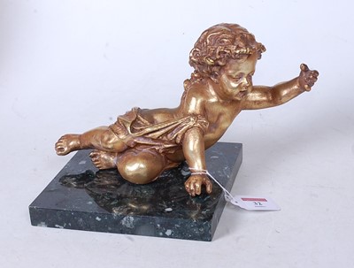 Lot 32 - A gilt painted model of a cherub in reclining...