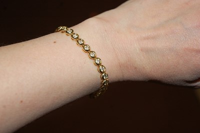 Lot 2332 - An 18ct yellow gold diamond line bracelet,...
