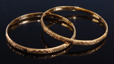 Lot 2171 - A pair of yellow metal oval bangles, each...