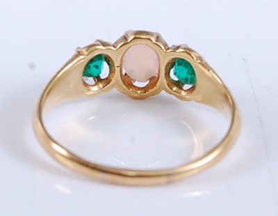 Lot 2534 - A yellow metal, opal and emerald three stone...