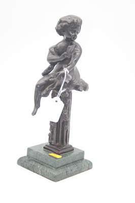 Lot 29 - A bronzed figure of putti in seated pose upon...