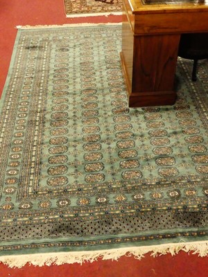 Lot 1180 - A Persian woollen green ground Bokhara rug,...