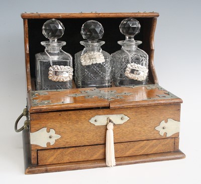 Lot 2330 - An Edwardian oak three-bottle tantalus, having...