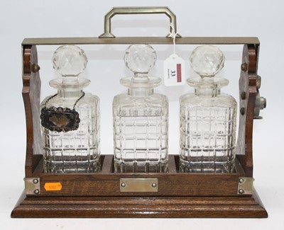 Lot 33 - An early 20th century oak three decanter...