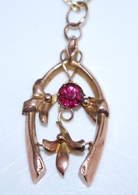 Lot 2573 - A rose metal horseshoe pendant, set with a...