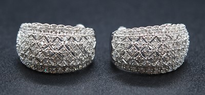 Lot 2694 - A pair of white metal diamond set half hoop...