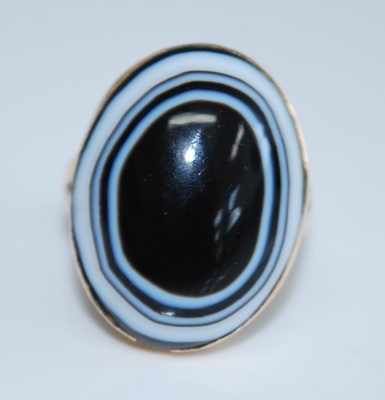 Lot 2741 - A yellow metal banded agate ring, featuring an...