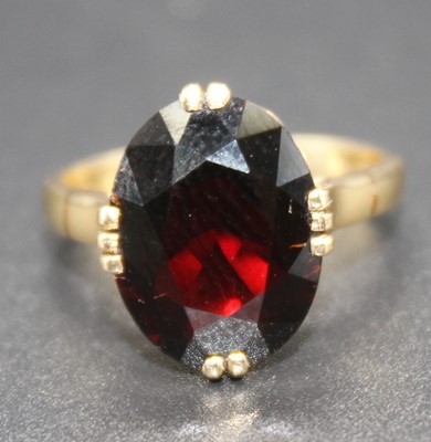 Lot 405 - A modern yellow metal garnet set dress ring,...