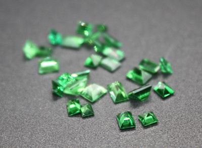 Lot 2834 - A collection of loose synthetic emeralds,...