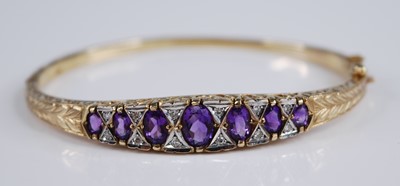 Lot 2234 - A 9ct gold, amethyst and diamond hinged bangle,...