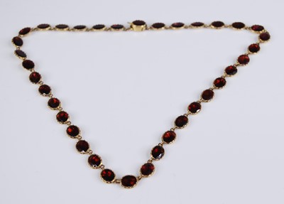 Lot 2282 - A yellow metal garnet necklet, comprising 36...