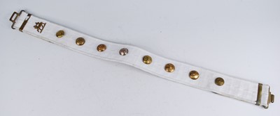 Lot 285 - A white canvas webbing belt adorned with a...