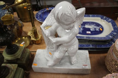 Lot 157 - A continental pottery putto, mounted upon a...