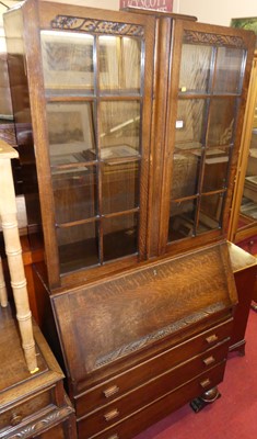 Lot 1249 - A 1930s oak bureau bookcase, having twin...