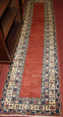 Lot 1188 - A Persian woollen red ground long hall runner,...