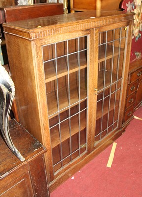 Lot 1223 - A 1930s oak lead glazed double door bookcase,...