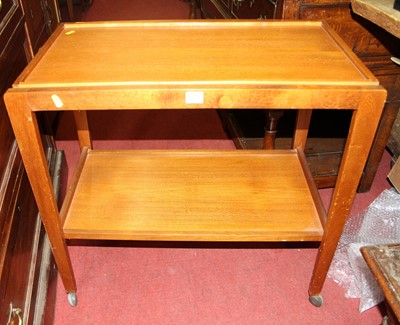 Lot 1289 - A 1970s teak two-tier tea trolley on roller...