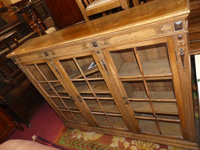 Lot 1377 - A 1930s oak three door glazed bookcase, w.141cm