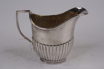Lot 250 - A George V silver cream jug, of half-reeded...