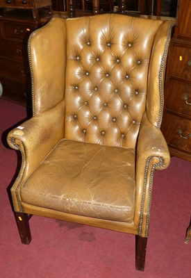 Lot 1336 - A tan leather buttoned upholstered wingback...