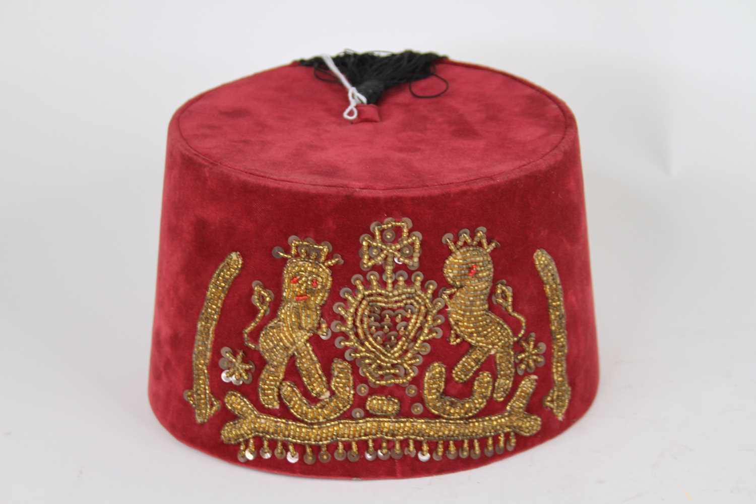 Lot 70 - A red velvet fez, embroidered with a beaded...
