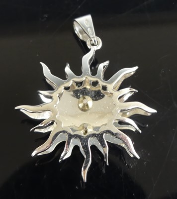 Lot 2588 - A white metal sun pendant, having a centre...